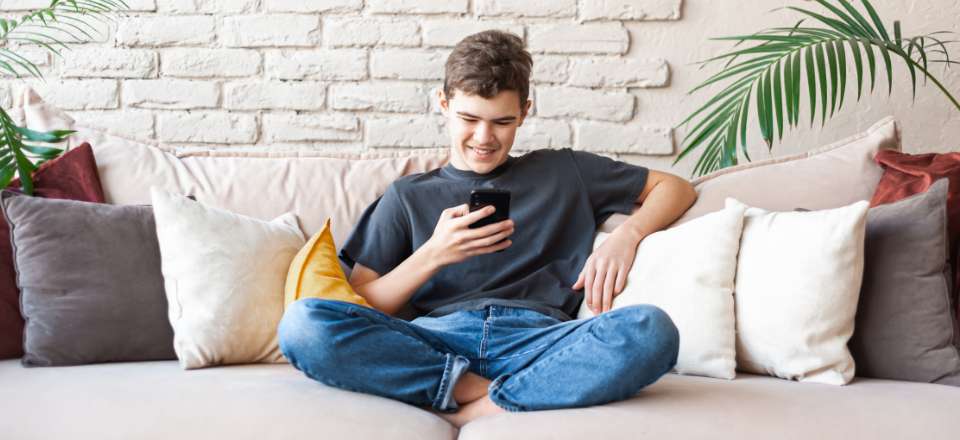Boy sitting on the couch and messing with his cell phone